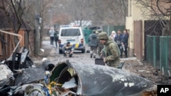 Yon solda lame Ikrenyen an enspekte debri sak sanble yon avyon yo desann nan vil Kyev peyi Ikren, Vandredi 25 Fevriye 2022. 