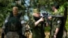 A Russian Army soldier looks through a sniper rifle scope as she and other soldiers guard a group of foreign journalists visiting a captured Ukrainian checkpoint and well-fortified trenches near Schastia town, on the territory which is under the Governmen
