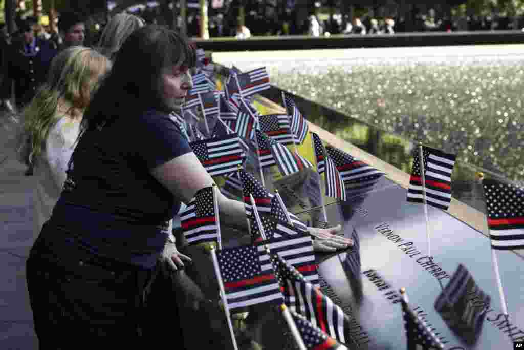 Family members place flowers on the south pool during the 9/11 Memorial ceremony on the 23rd anniversary of the Sept. 11, 2001 attacks, in New York. 