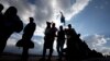People are silhouetted against a late afternoon sun as they queue to see the remains of Nelson Mandela at the Union Buildings in Pretoria, South Africa, Dec. 11, 2013, where his body lies in state for three days.