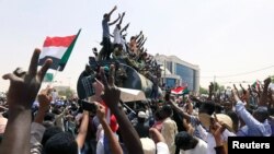 Los oficiales y manifestantes militares sudaneses montan sobre un camión cisterna militar para protestar contra el anuncio del ejército de que el presidente Omar al-Bashir sería reemplazado por un consejo de transición liderado por militares.
