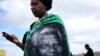 A woman, draped in a cloth with an image of former South African President Nelson Mandela, uses a mobile phone during Mandela's funeral at his ancestral village of Qunu in Eastern Cape province, south of Johannesburg, Dec. 15, 2013.