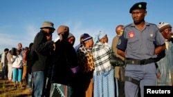 File - A police officer looks on at a voting station during the Lesotho national election in Magkhoakhoeng village outside the capital Maseru, Feb. 28, 2015. 
