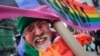 L'artiste Gilbert Baker, créateur du drapeau arc-en-ciel, porte une pancarte " Boycottons l'homophobie" lors de la parade pour la Saint Patrick à New York, le 17 mars 2014 
