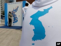 一名韩国妇女在首尔张贴的朝鲜半岛地图上贴上祈祷和平的字条。 (2016年4月26日)