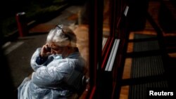 El doctor Jean-Noel Lepront, con traje protector y máscara facial, hace una llamada telefónica fuera de un centro de emergencia COVID-19 dentro de un gimnasio en Champigny-sur-Marne, cerca de París.