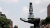 Un hombre camina junto a una escultura frente a un edificio de la compañía petrolera estatal de Venezuela PDVSA en Caracas, Venezuela. 17 de mayo de 2019. 